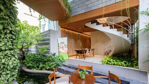 A modern indoor garden with a spiral staircase, wooden furniture, and a small pond. - Babylon Garden Condotel (Da Nang)
