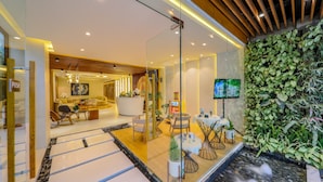 A modern hotel lobby with a reception desk, seating area, and a wall-mounted TV. - Babylon Garden Condotel (Da Nang)