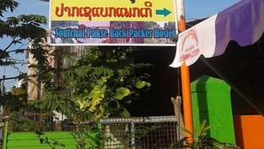 A signboard for a hostel with contact details and a travel agency. - Soutchai Pakse Backpacker Hostel (Pakse)