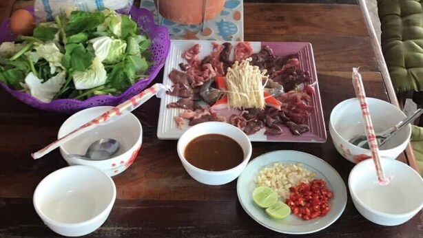 A table with various food items and a clay pot. - Soutchai Pakse Backpacker Hostel (Pakse)
