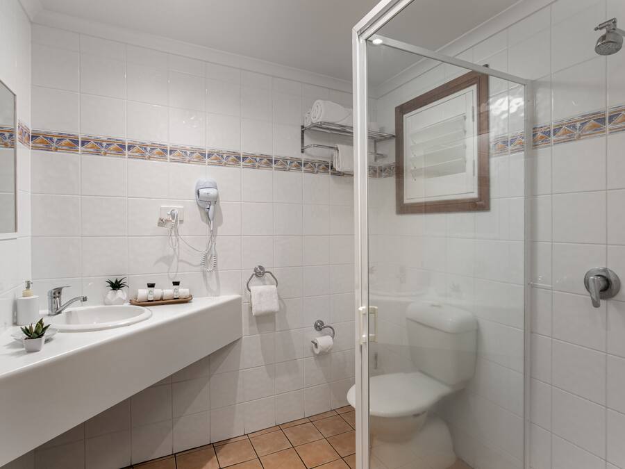 Ein modernes Badezimmer mit Duschkabine aus Glas, einem weißen Waschbecken mit Spiegel und einer Toilette.
