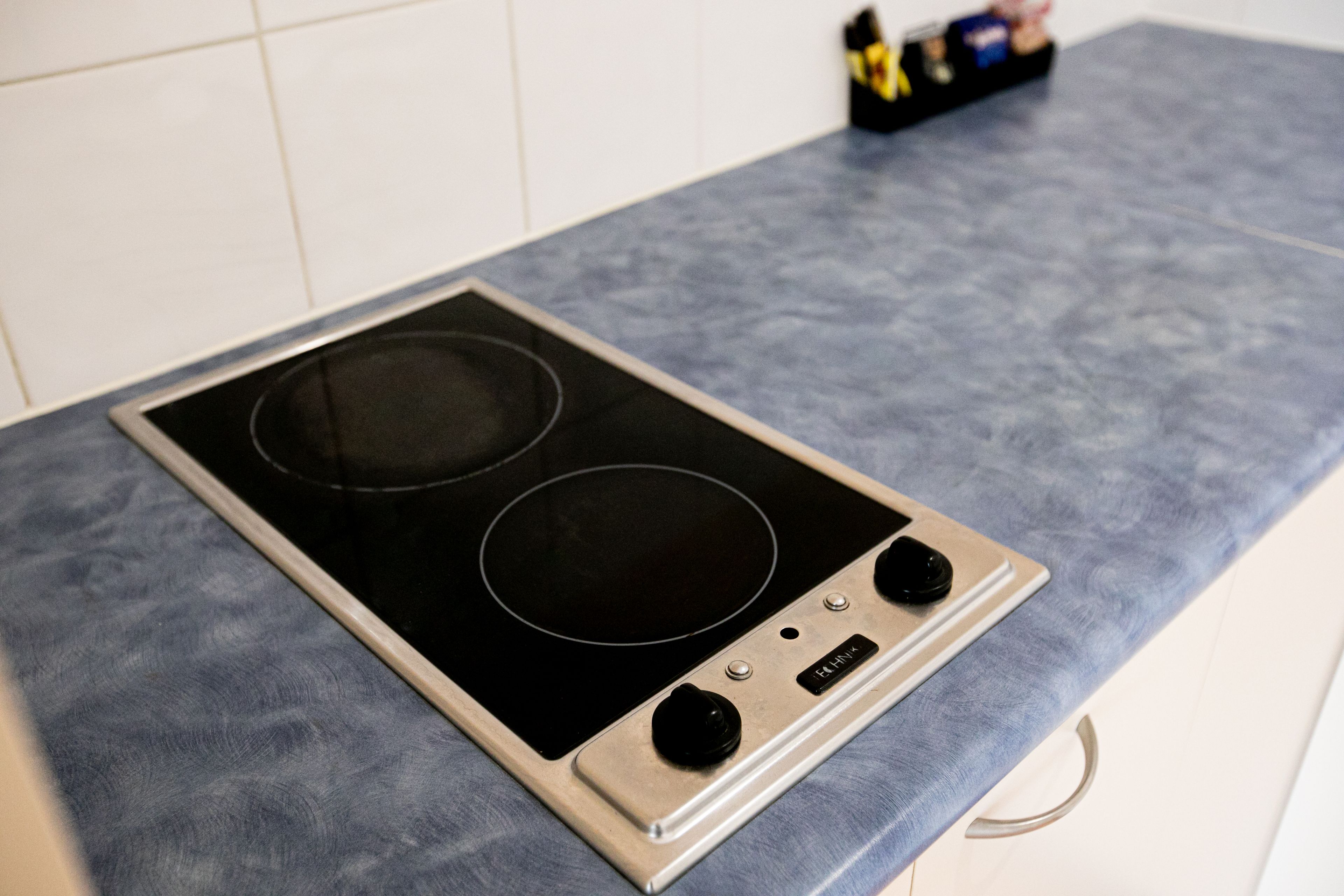 A kitchen with a black induction cooktop and a stainless steel backsplash.