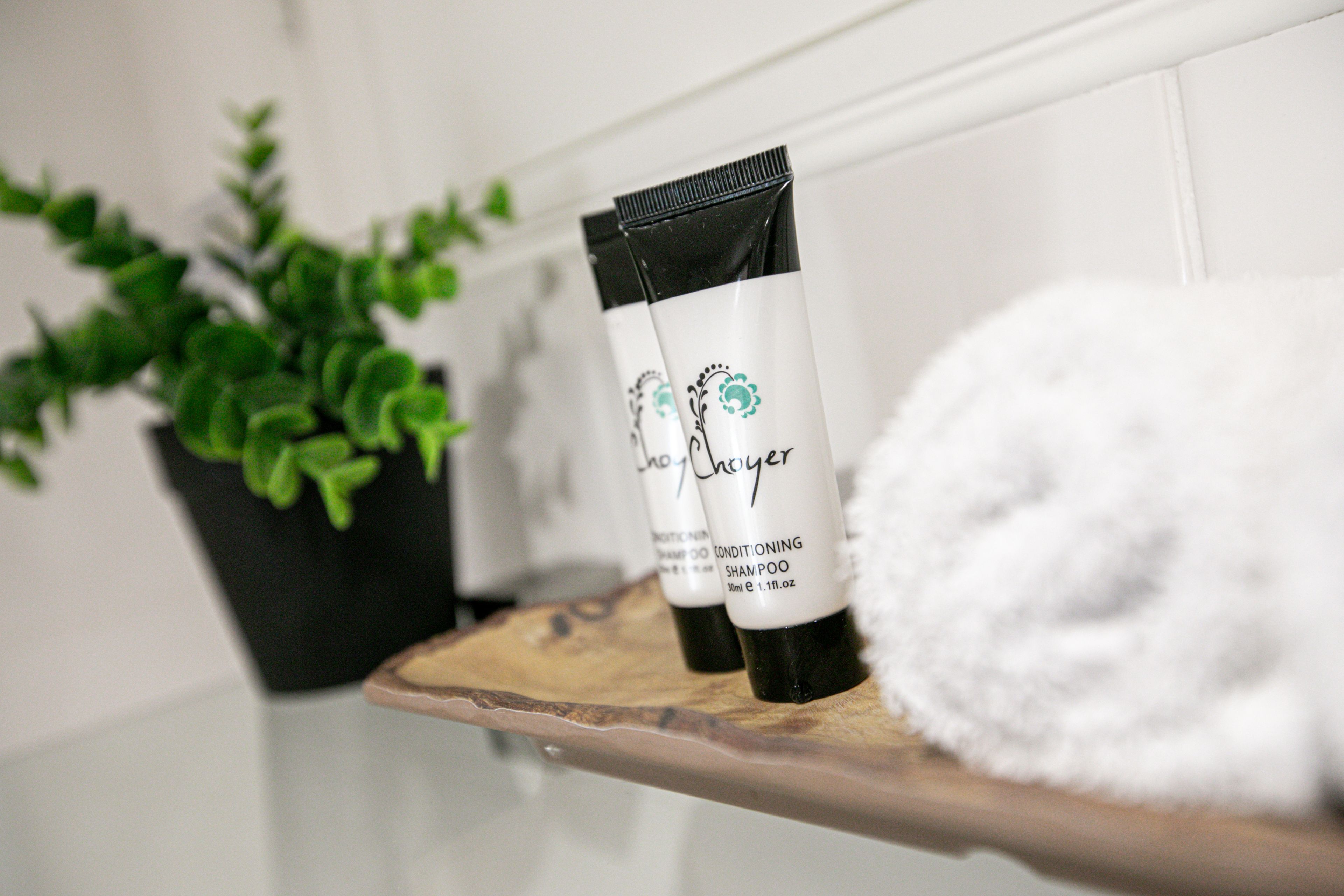 A bathroom shelf with a white towel and two bottles of shampoo.