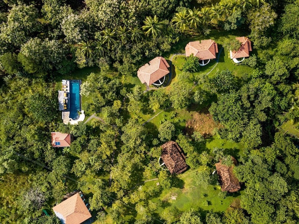 Vue aérienne d’une propriété comprenant plusieurs bâtiments, une piscine et une végétation luxuriante.