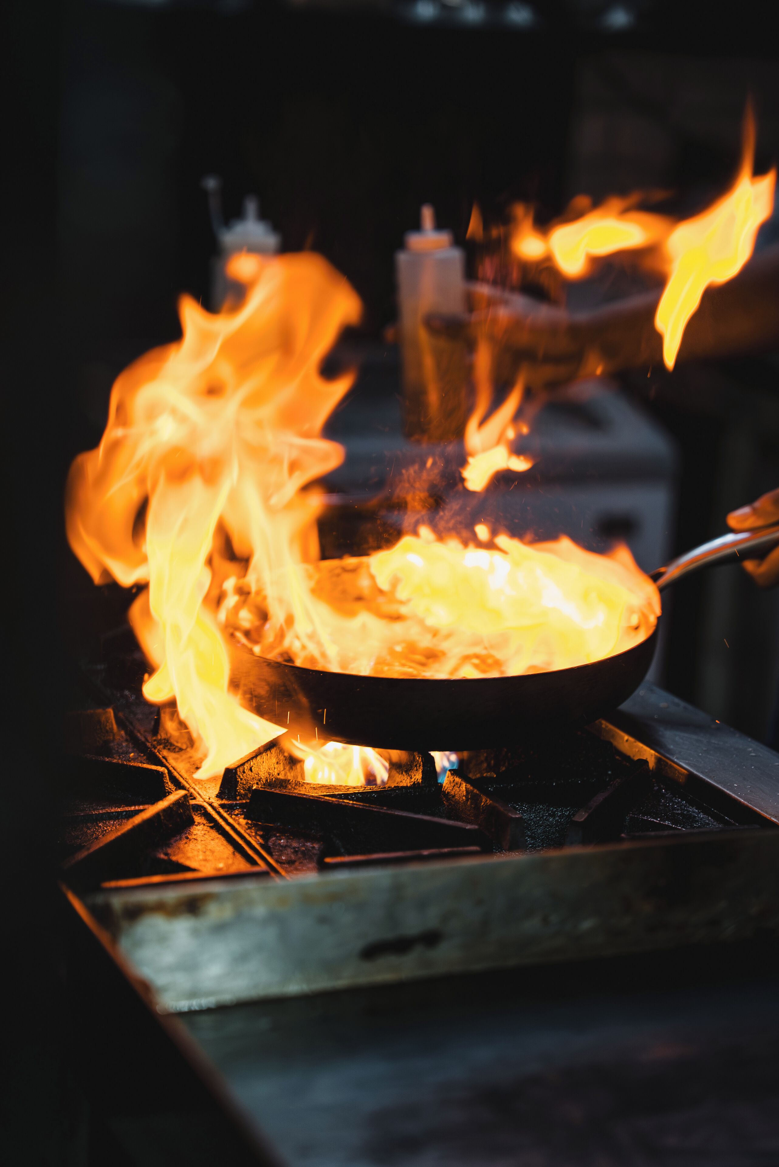 A close-up of a pan on a stove with flames.