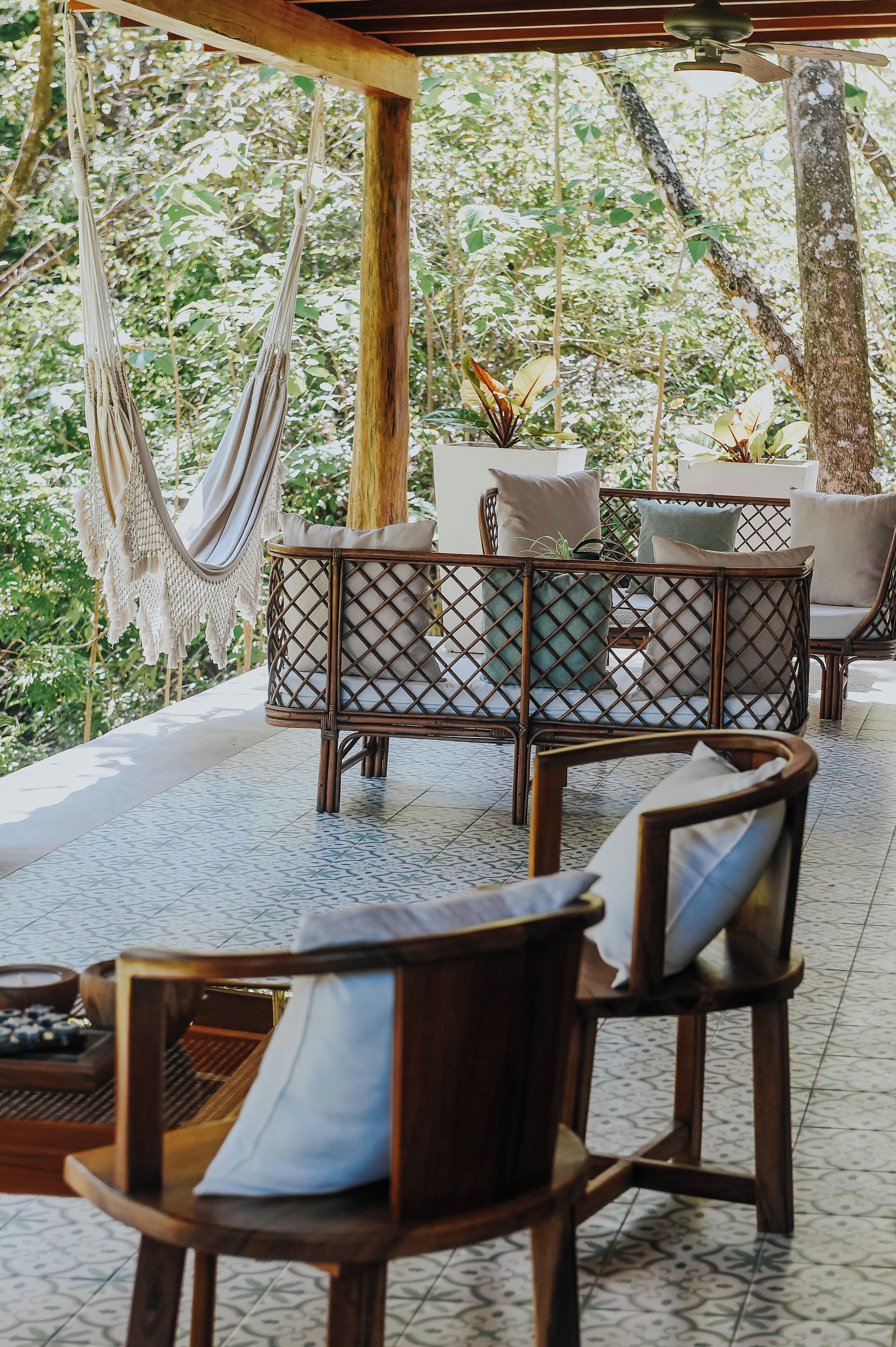 A covered outdoor seating area with wicker furniture and a hammock.