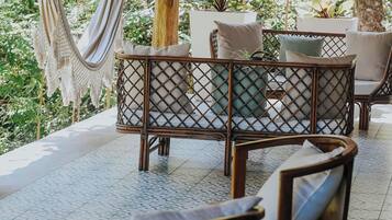 A covered outdoor seating area with wicker furniture and a hammock.