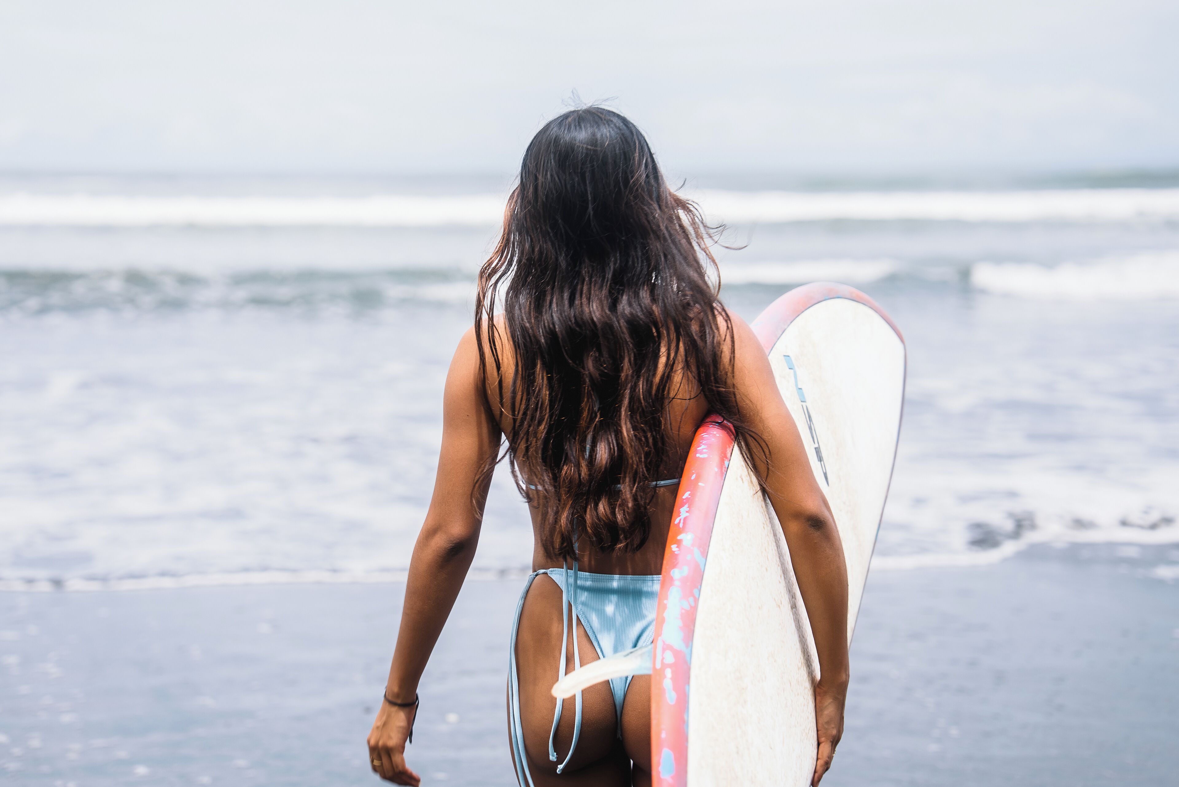 A person carrying a surfboard on a beach.
