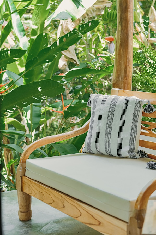 Un banc en bois avec un coussin à rayures, placé dans un jardin luxuriant.