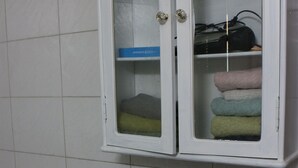Un baño con un mueble blanco que contiene artículos de tocador, toallas y una caja azul.