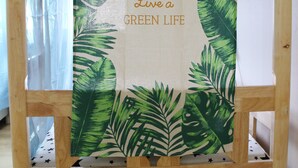 Una silla de madera con estampado de hojas tropicales y un mensaje que promueve un estilo de vida ecológico.