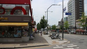 Vista de la calle con un restaurante a la izquierda, un paso de peatones y motocicletas estacionadas.