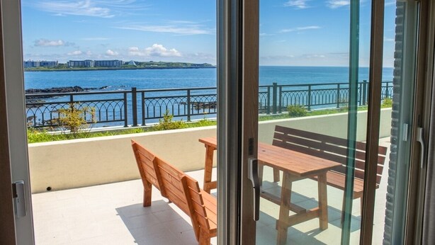 A balcony with a view of the sea, wooden benches, and a table. - Haemorat (Seogwipo)