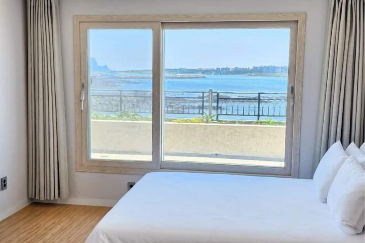 Una habitación de hotel con un ventanal grande, una cama y cortinas.