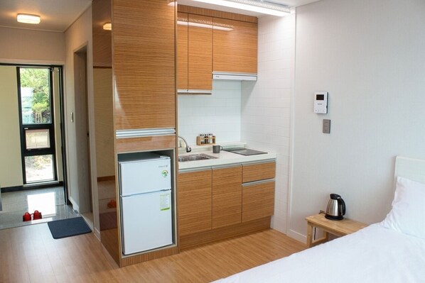 Una habitación de hotel moderna con kitchenette, una cama y una mesita de noche.