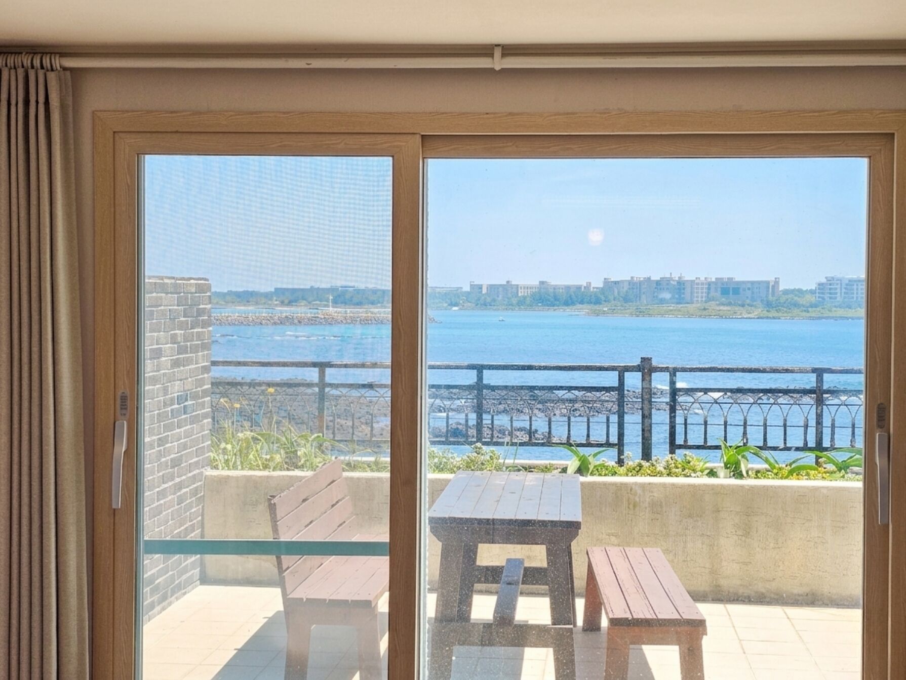 A balcony with a view of a body of water and a distant cityscape.