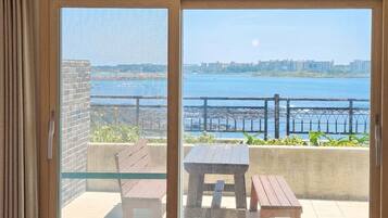 A balcony with a view of a body of water and a distant cityscape.