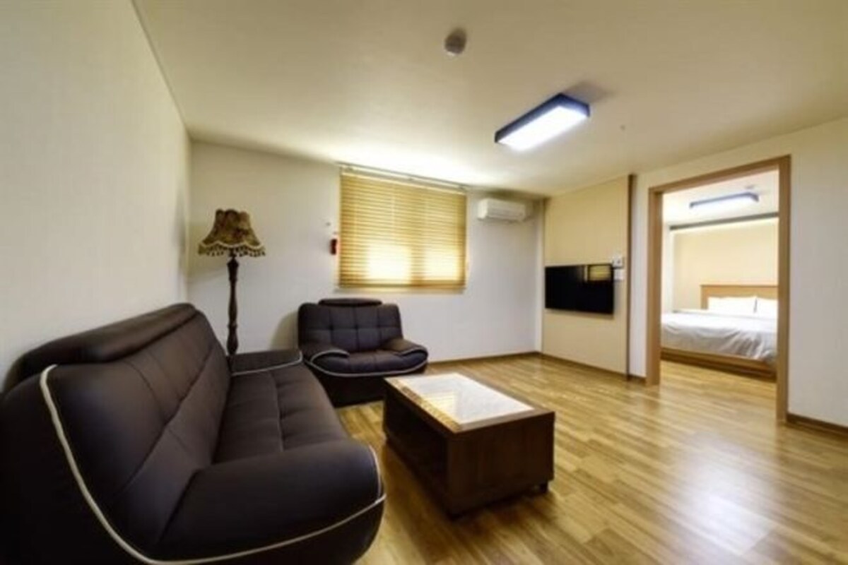A modern room with a sofa, a chair, a coffee table, and a bed.