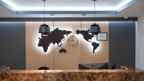 Een receptiebalie met een wereldkaart, een klok en twee hanglampen.