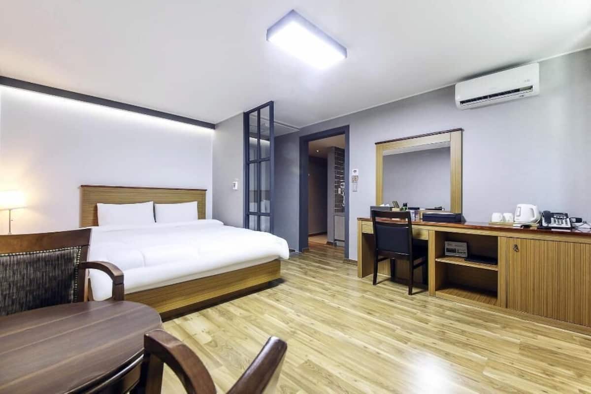 Une chambre d’hôtel équipée d’un lit, d’un bureau, d’une chaise et d’un petit coin cuisine.