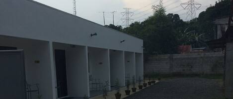 A building with a row of potted plants and a gravel pathway leading to a door.