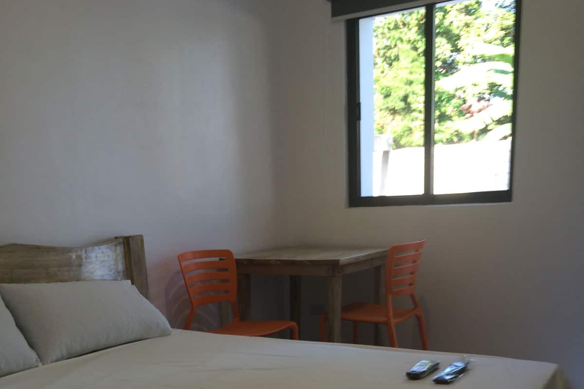 A room with a bed, a small table, two chairs, and a window.