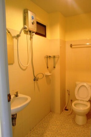 A small bathroom with a toilet, sink, and shower unit.