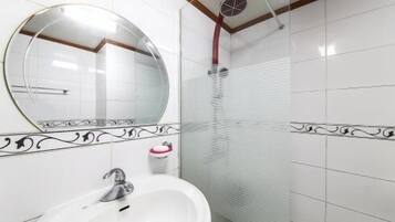 A bathroom with a round mirror, a sink, and a shower.