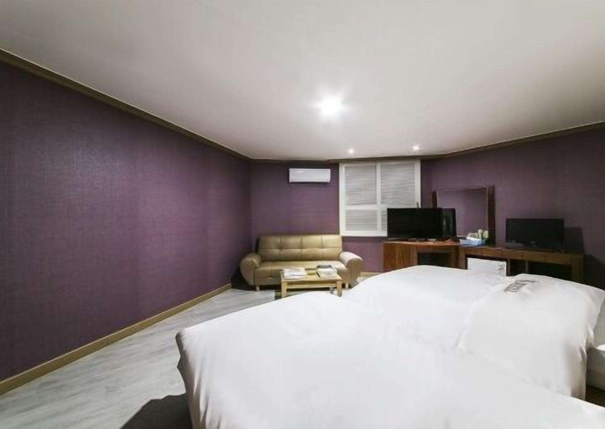 A hotel room with a bed, a sofa, a TV, and a desk.