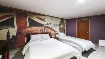A bedroom with two single beds, a large mural on the wall, and a wooden door.