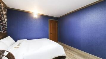 A hotel room with a bed, a wooden door, and blue walls.