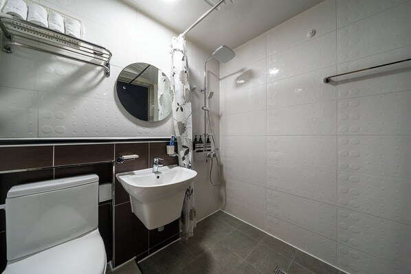 Un baño con inodoro, lavamanos, ducha y perchero para toallas.