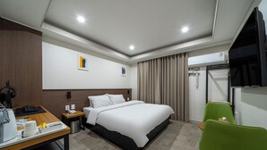 A hotel room with a bed, a desk with a telephone, a trash bin, a green chair, and an air conditioning unit. - Hotel Yaja Jecheon Station (Jecheon)