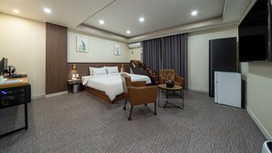 A hotel room with a bed, a desk with a computer, a chair, a small table, a TV, and a refrigerator. - Hotel Yaja Jecheon Station (Jecheon)