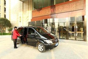 A black car parked in front of a building with a sign in Chinese characters.