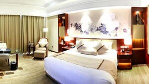A hotel room with a large bed, a desk, and a chair. - New Century Hotel Yiwu (Jinhua)