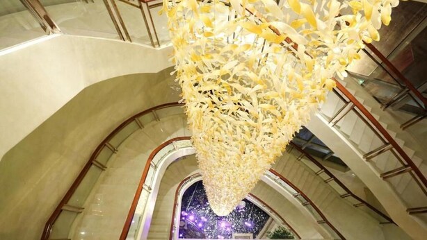 A spacious atrium with a high ceiling and a large, hanging chandelier made of white flowers. - New Century Hotel Yiwu (Jinhua)
