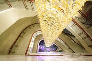A spacious atrium with a high ceiling and a large, hanging chandelier made of white flowers. - New Century Hotel Yiwu (Jinhua)