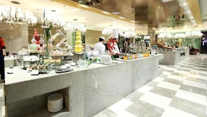 A buffet area with a marble counter, various food items, and a checkered floor. - New Century Hotel Yiwu (Jinhua)