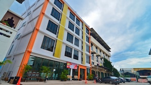 Un immeuble à plusieurs étages doté d’une architecture moderne, caractérisé par de grandes fenêtres et une palette de couleurs dominante en orange et blanc.