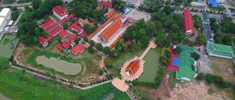 An aerial view of a residential area with multiple houses, a large water body, and a distinct temple structure.