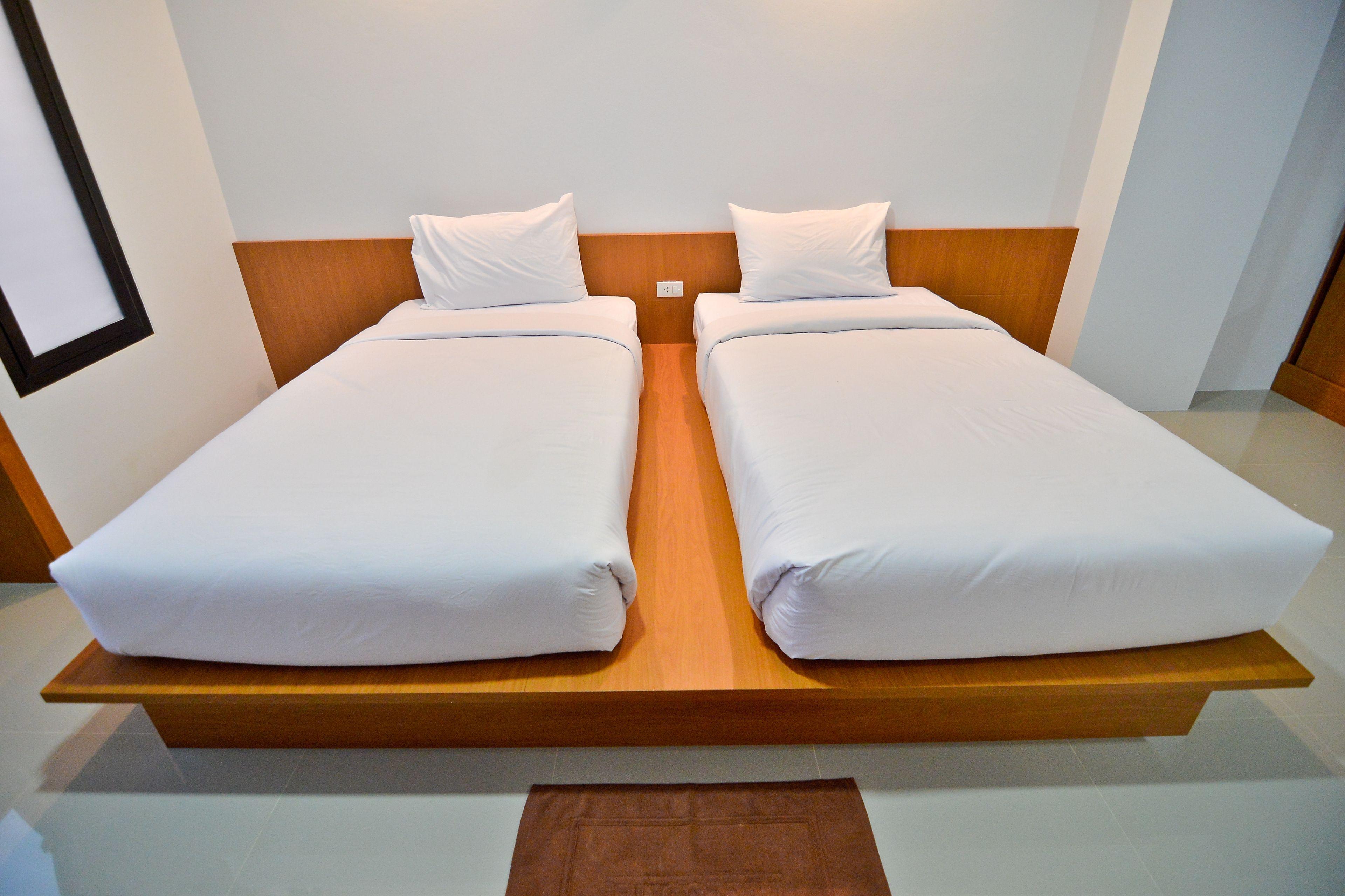 A double bed with wooden headboard and white bedding in a hotel room.