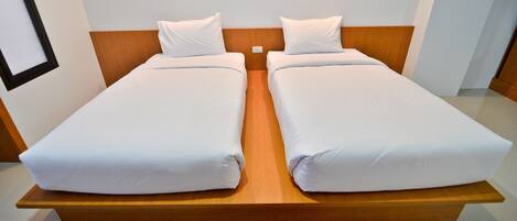 A double bed with wooden headboard and white bedding in a hotel room.
