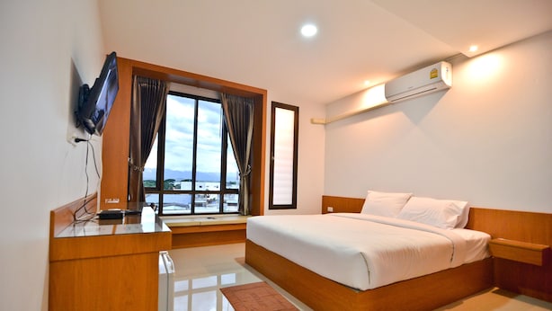 Une chambre d’hôtel moderne dotée d’un grand lit, d’un bureau avec un téléviseur à écran plat, d’une fenêtre avec des rideaux et d’un appareil de climatisation.