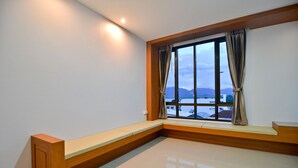 Une pièce dotée d’une grande fenêtre, d’un banc et offrant une vue sur un plan d’eau et des montagnes.
