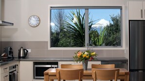 A modern kitchen with a dining area, a clock, and a window with a mountain view.