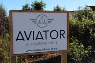 Señalización de 'AVIATOR ACCOMMODATION' con una dirección web.