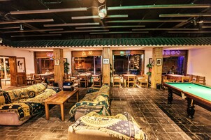 A traditional-style room with a pool table, sofas, and wooden furniture.