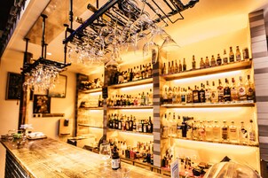 A bar with multiple shelves of liquor bottles, a wooden bar counter, and hanging wine glasses.