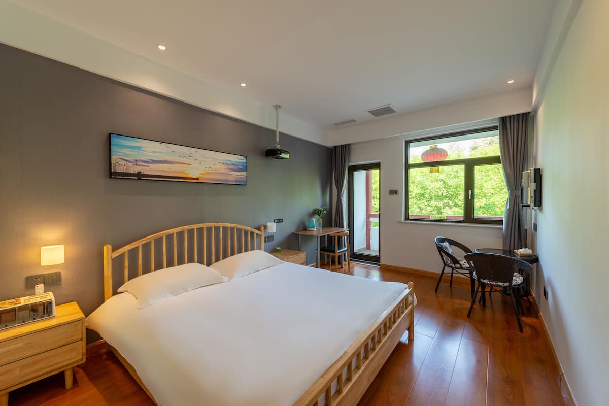 Een hotelkamer met een groot bed, nachtkastje, lamp en een schilderij aan de muur.